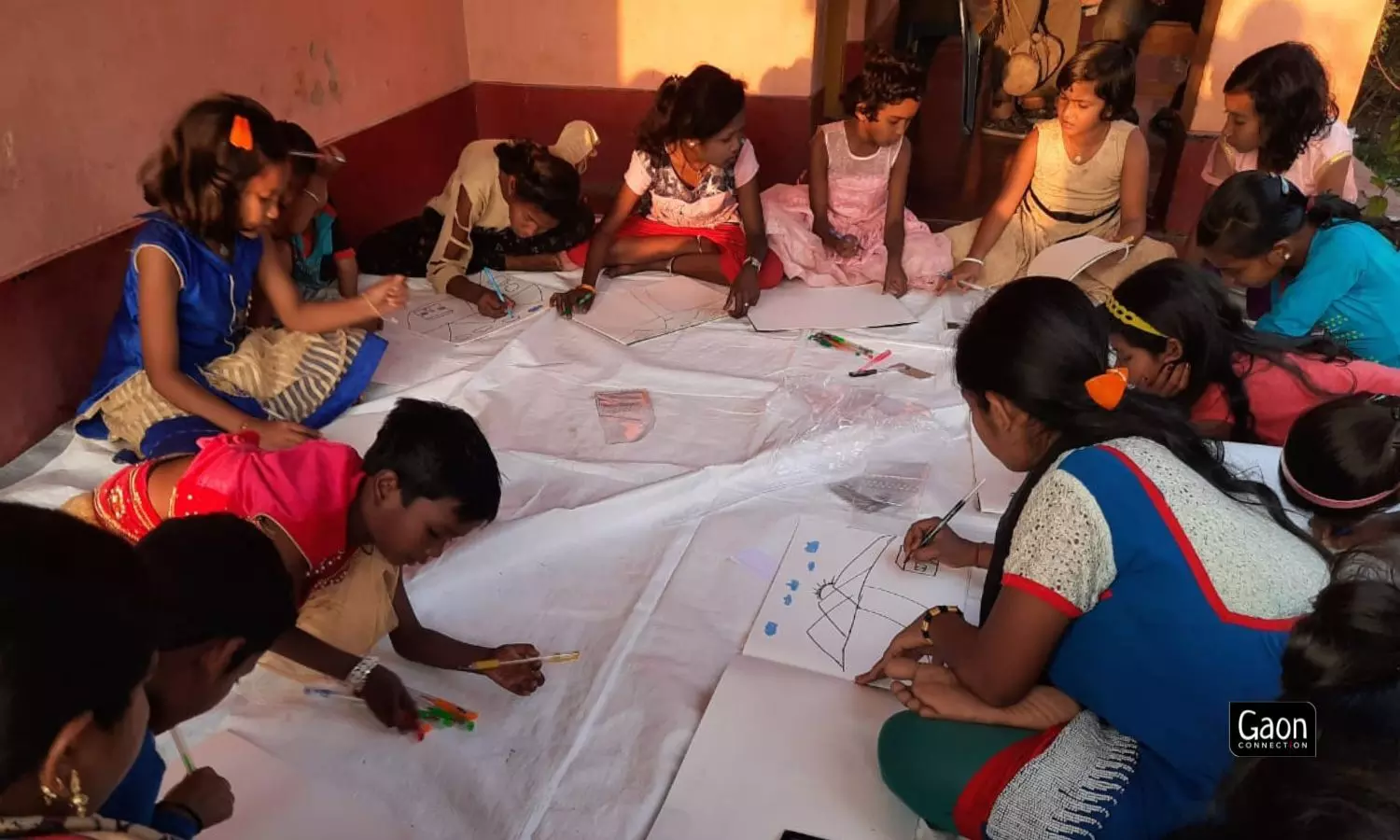 Sitting around him on a white sheet spread out on the floor, children pay close attention to Mohanti who sits on a bench and paints on an easel.